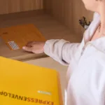 Seseorang menyimpan amplop ekspres ke dalam lemari arsip untuk pengiriman dokumen yang aman