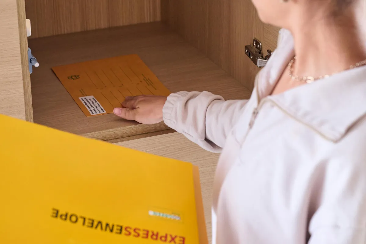 Seseorang menyimpan amplop ekspres ke dalam lemari arsip untuk pengiriman dokumen yang aman